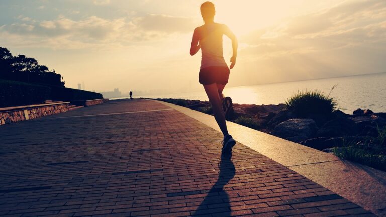 A woman jogging along a seaside promenade at sunrise